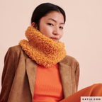 Model met een volumineuze oranje gebreide WOW-Loopy-col