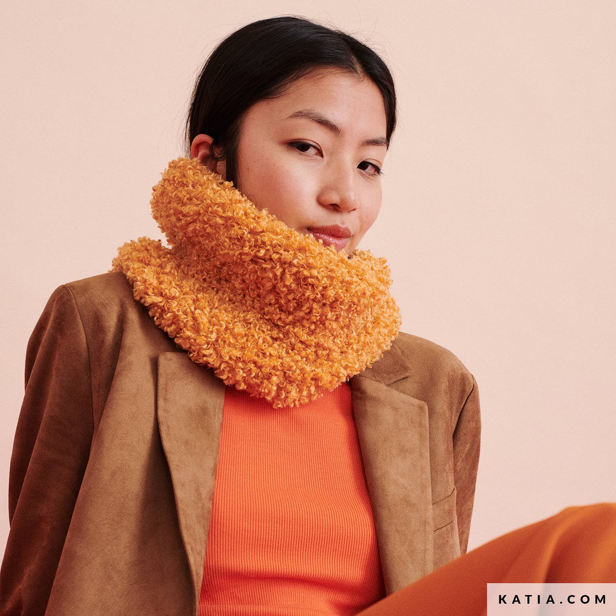 Model met een volumineuze oranje gebreide WOW-Loopy-col
