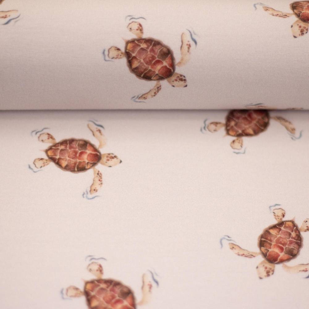 Swafing Aurich katoenjersey stof met schattige schildpadden op lichtbeige achtergrond, rekbare tricot geschikt voor baby- en dameskleding.